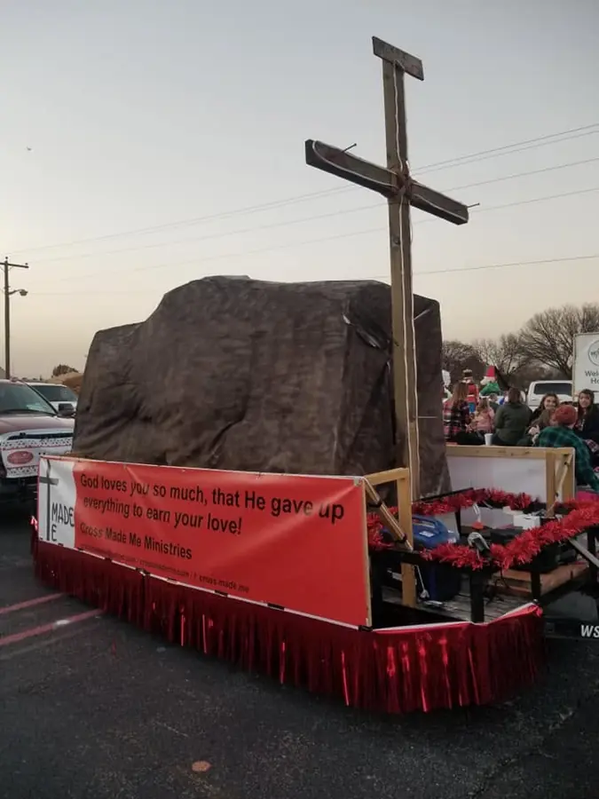 Cross Made Me Ministries parade float featuring a large cross and message banner
